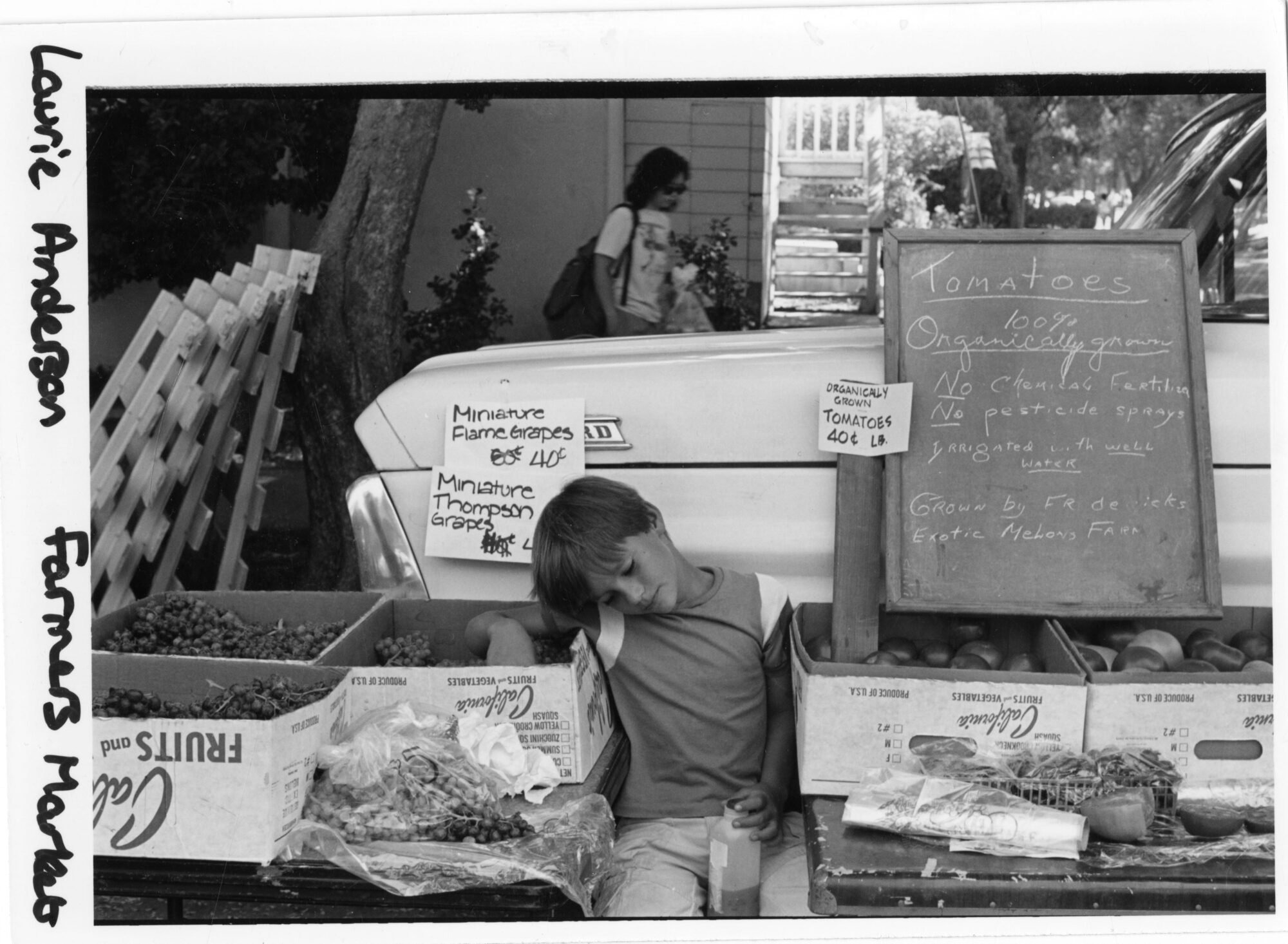 male child resting his eyes at a stand selling produce 