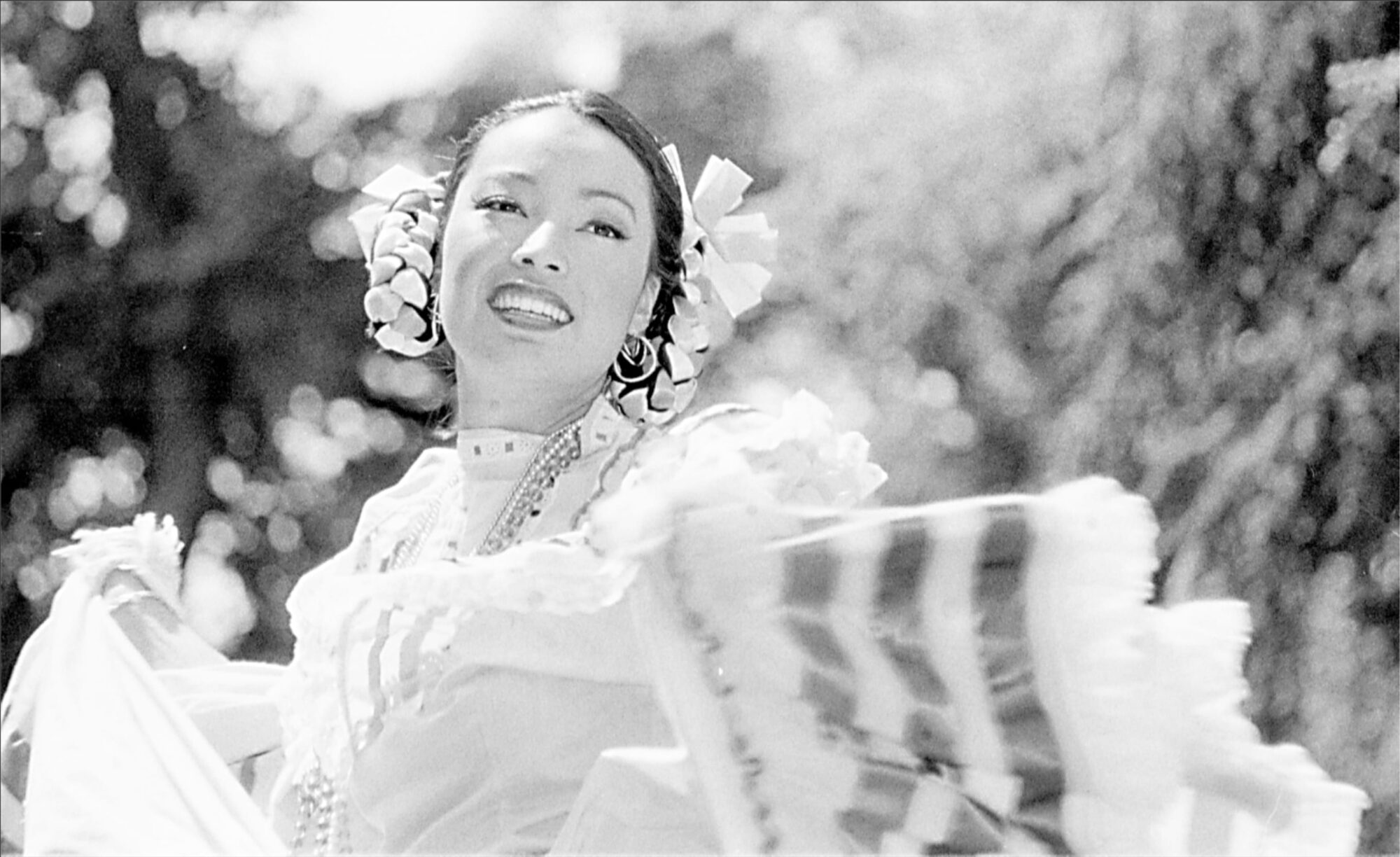 Close up of a female dancer in traditional folk garb with ribbons braided into her hair.