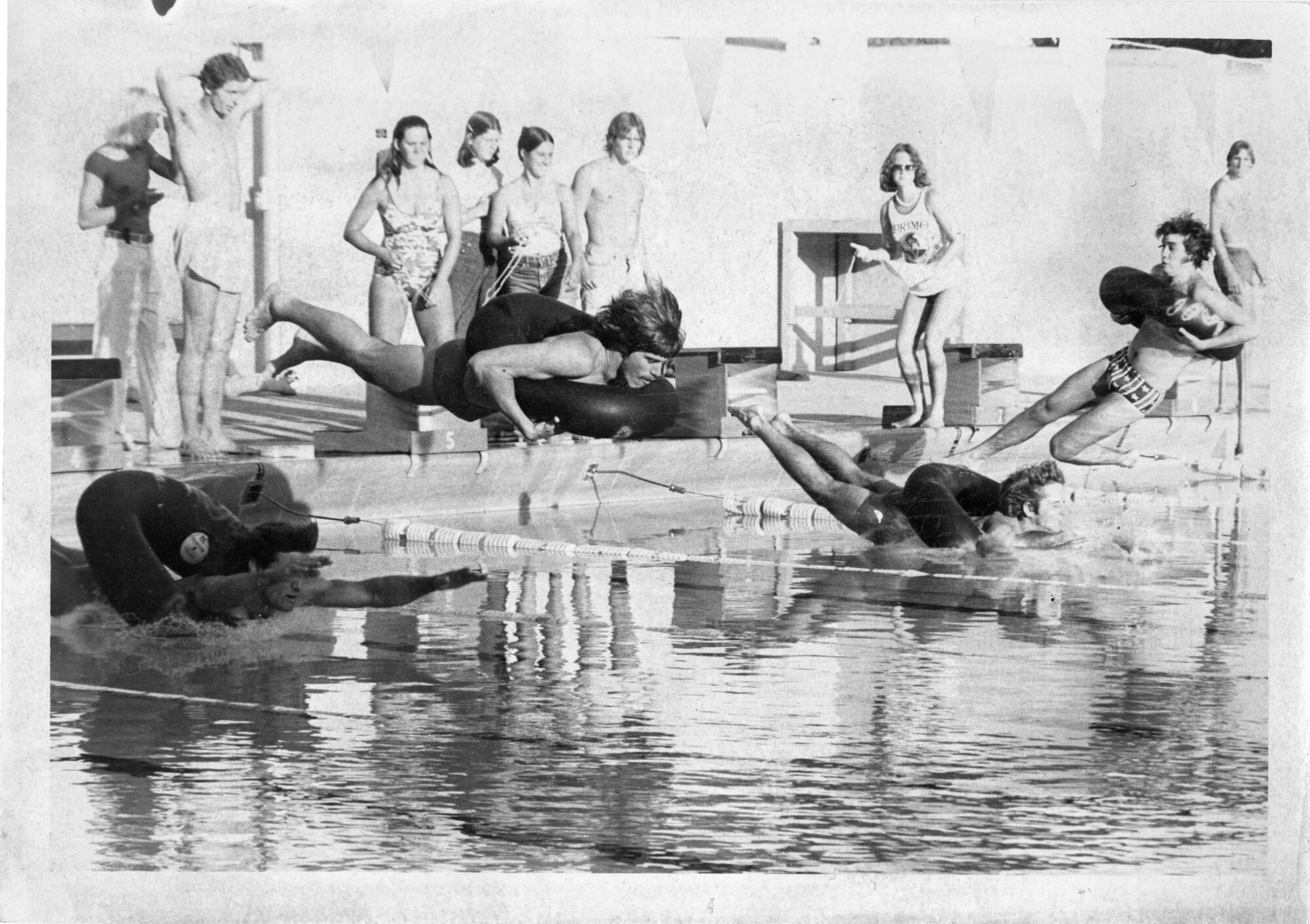 students jumping into a pool wearing large inner tubes