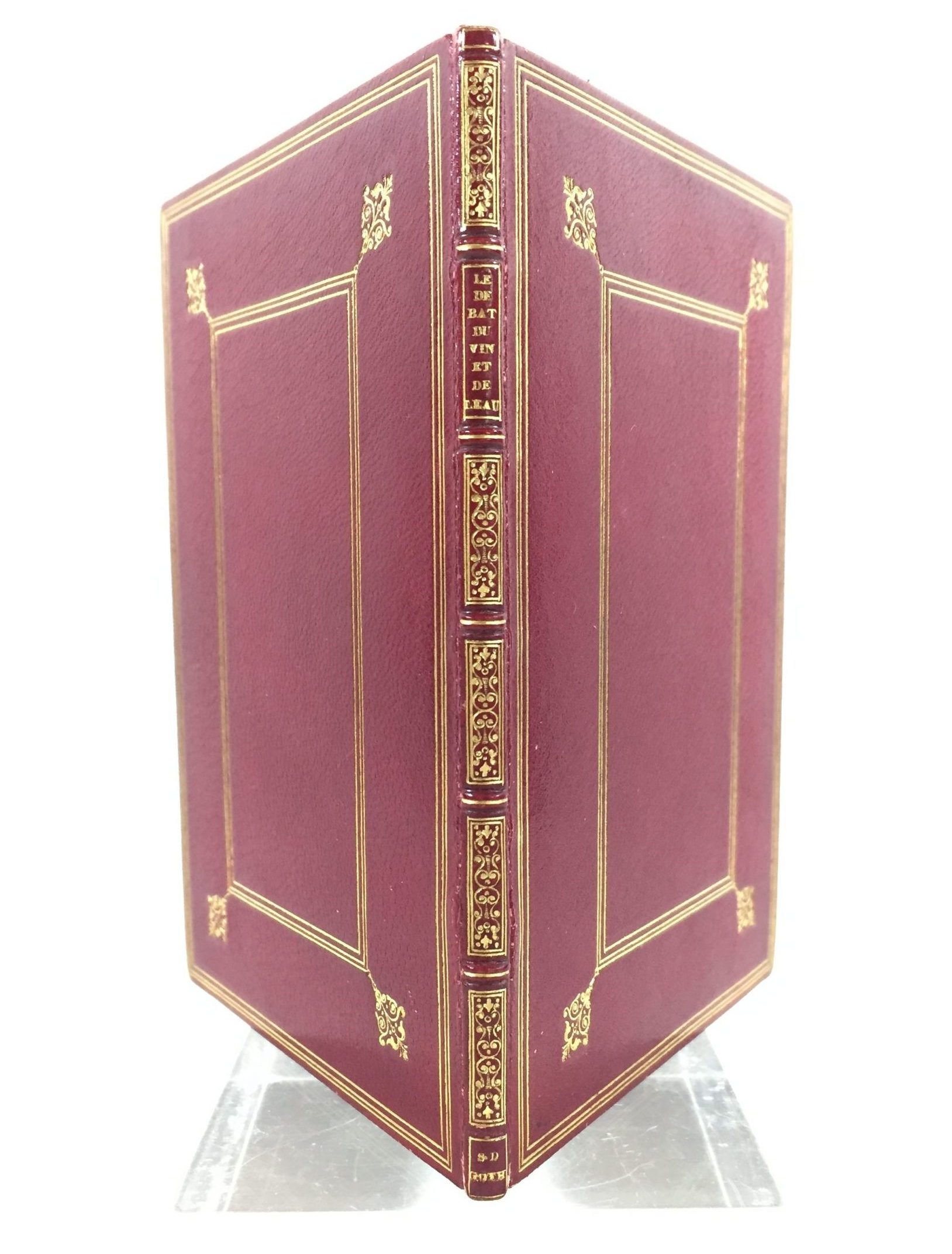 red cover of partially open rare book with gold trim