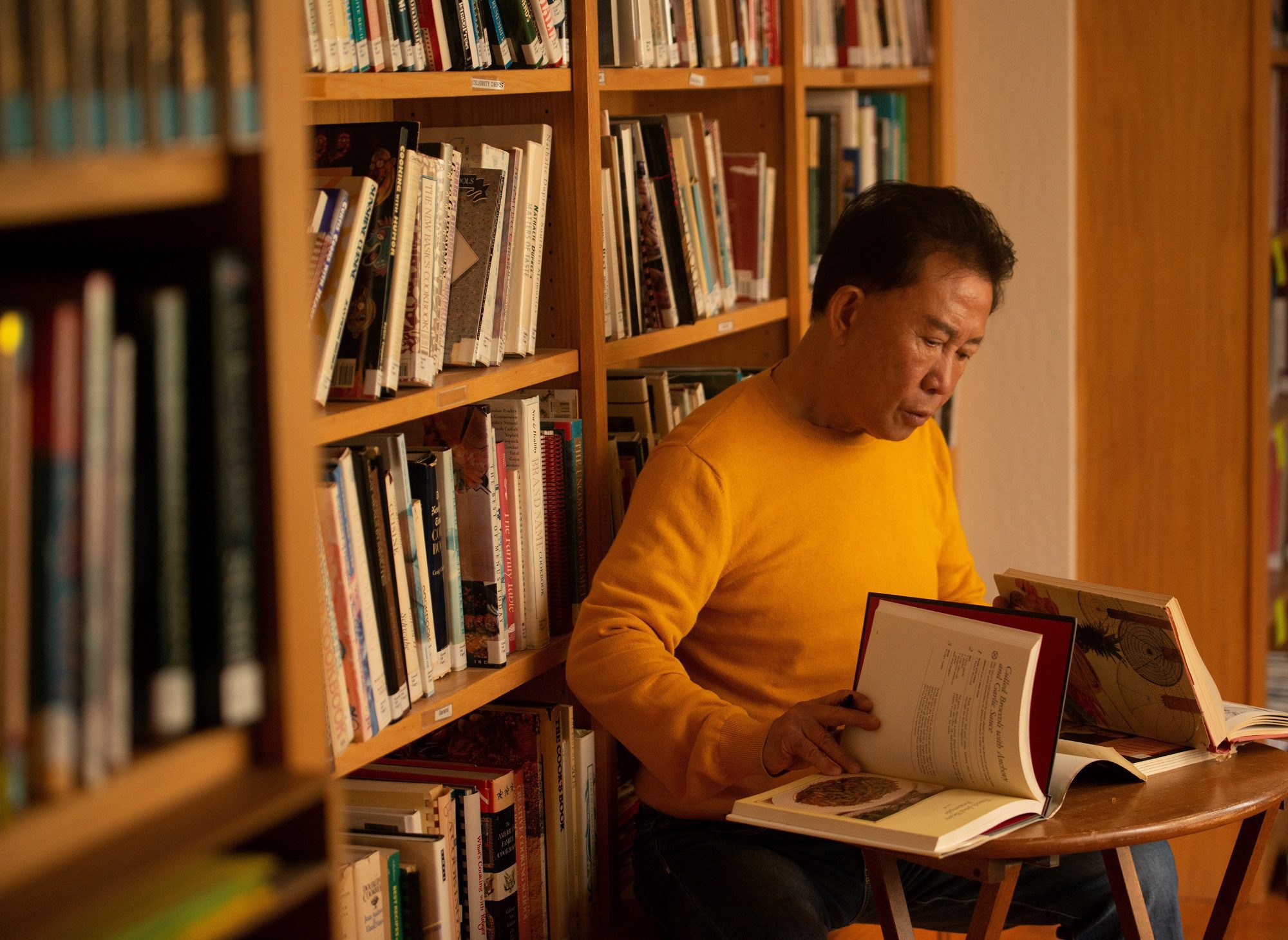 Martin Yan researching with cookbooks in his home