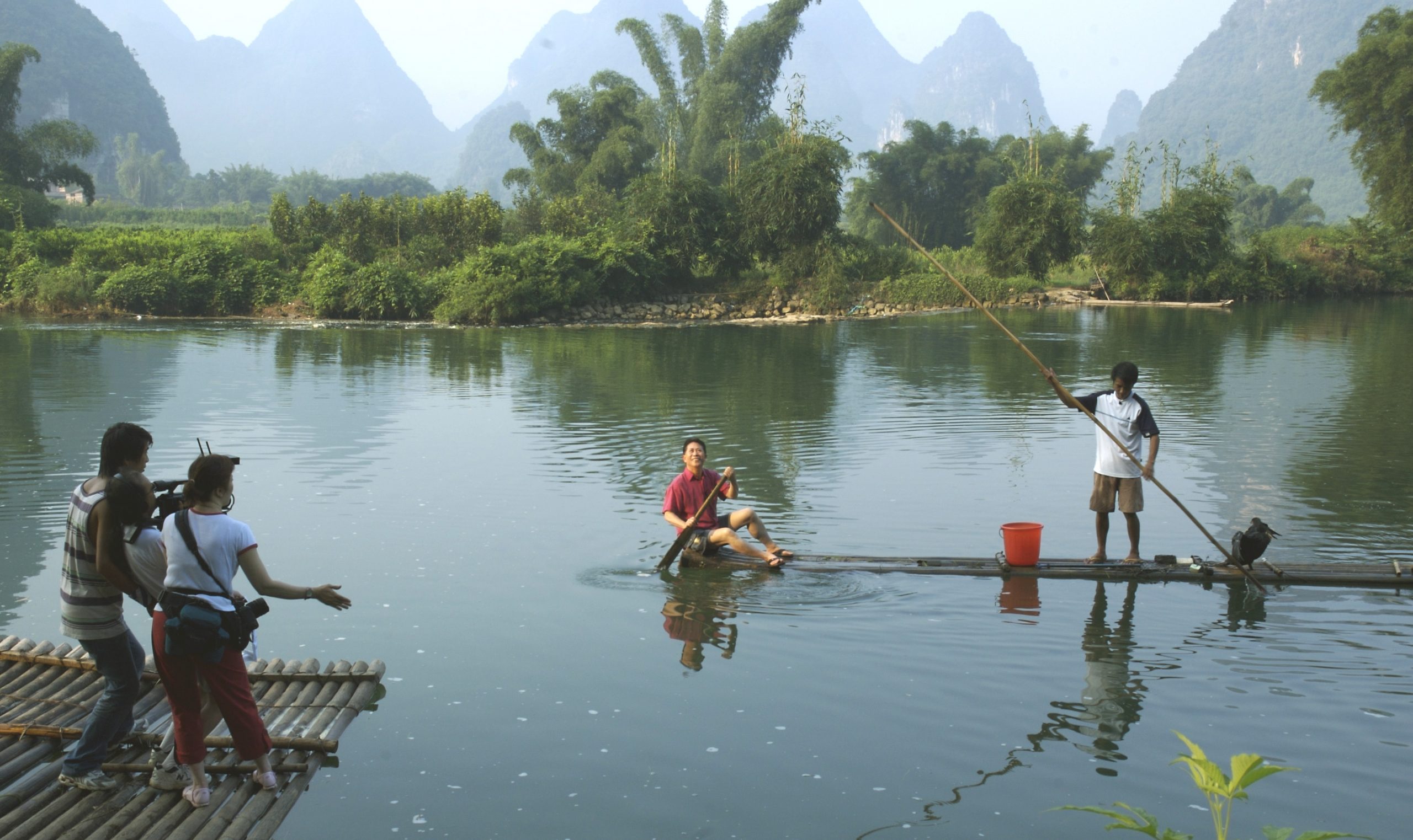 Martin Yan on a river in Yangshuo, China, with misty mountains in the background