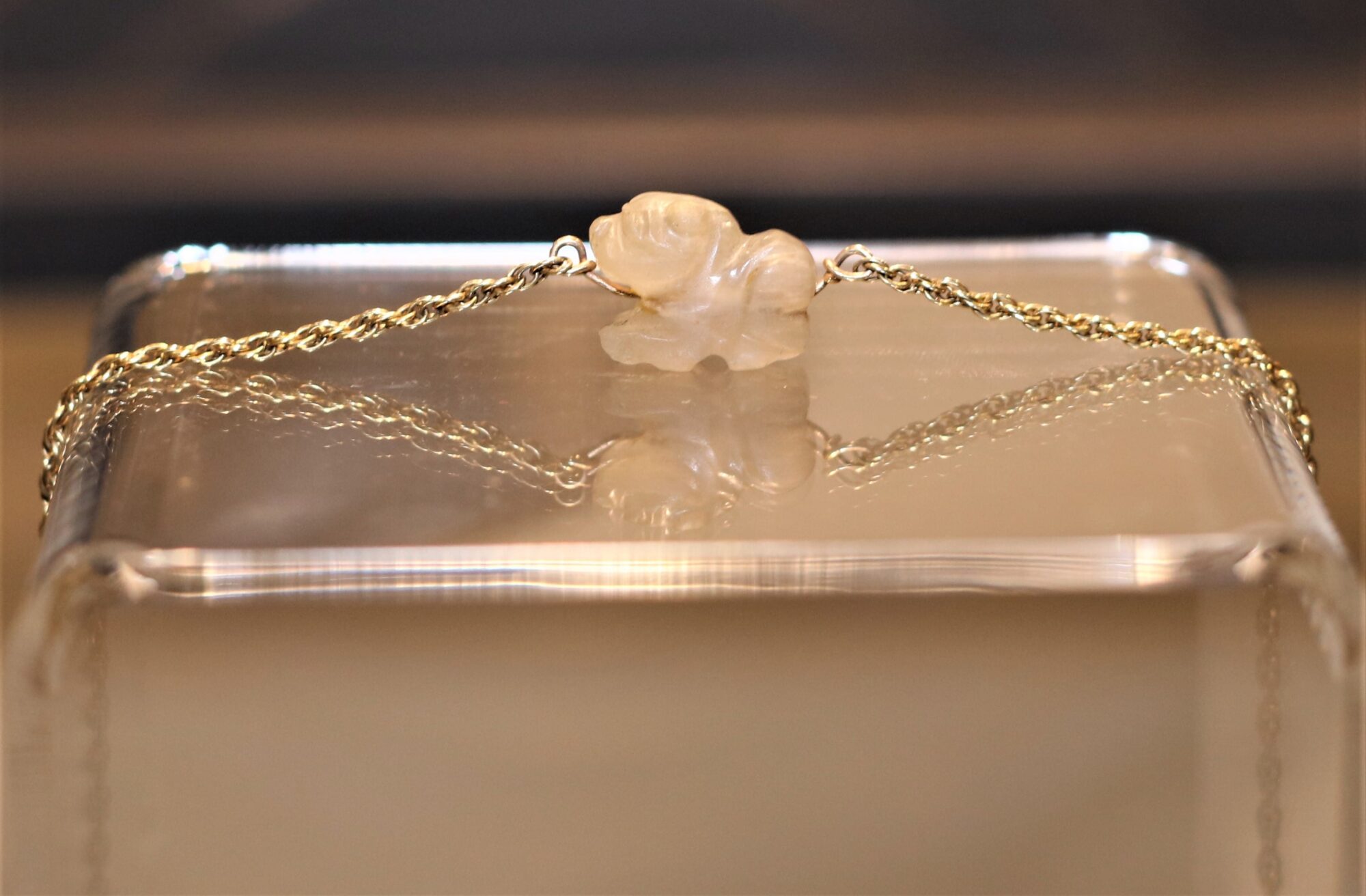 Glass-like bead sculpted into an animal shape on a chain.