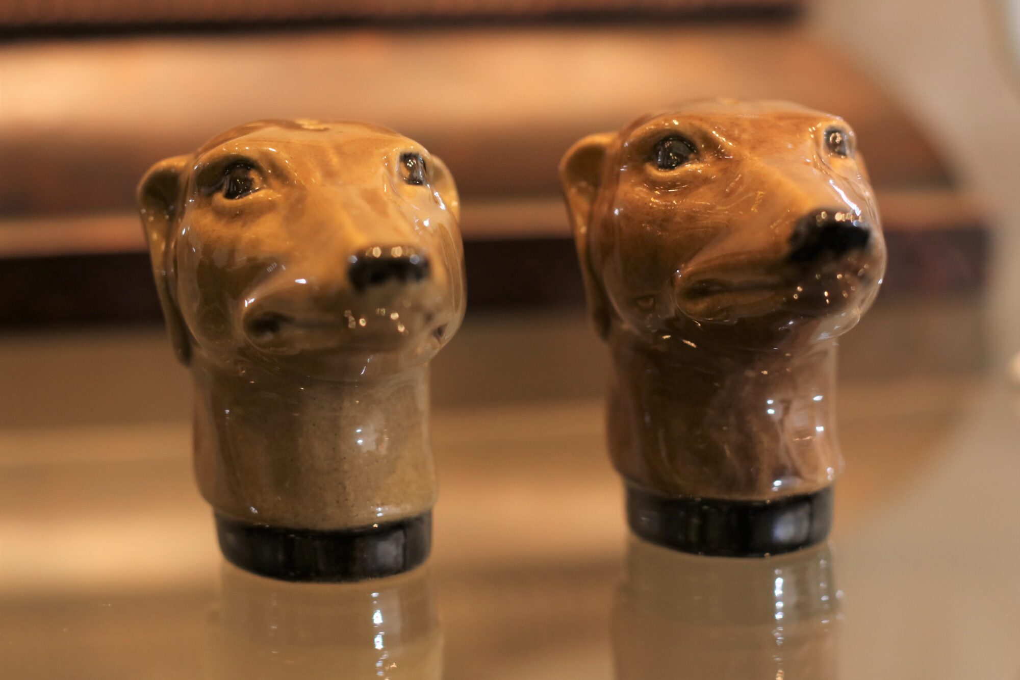 Ceramic salt and pepper shakers in the shape of tan colored greyhound heads side by side facing the viewer.