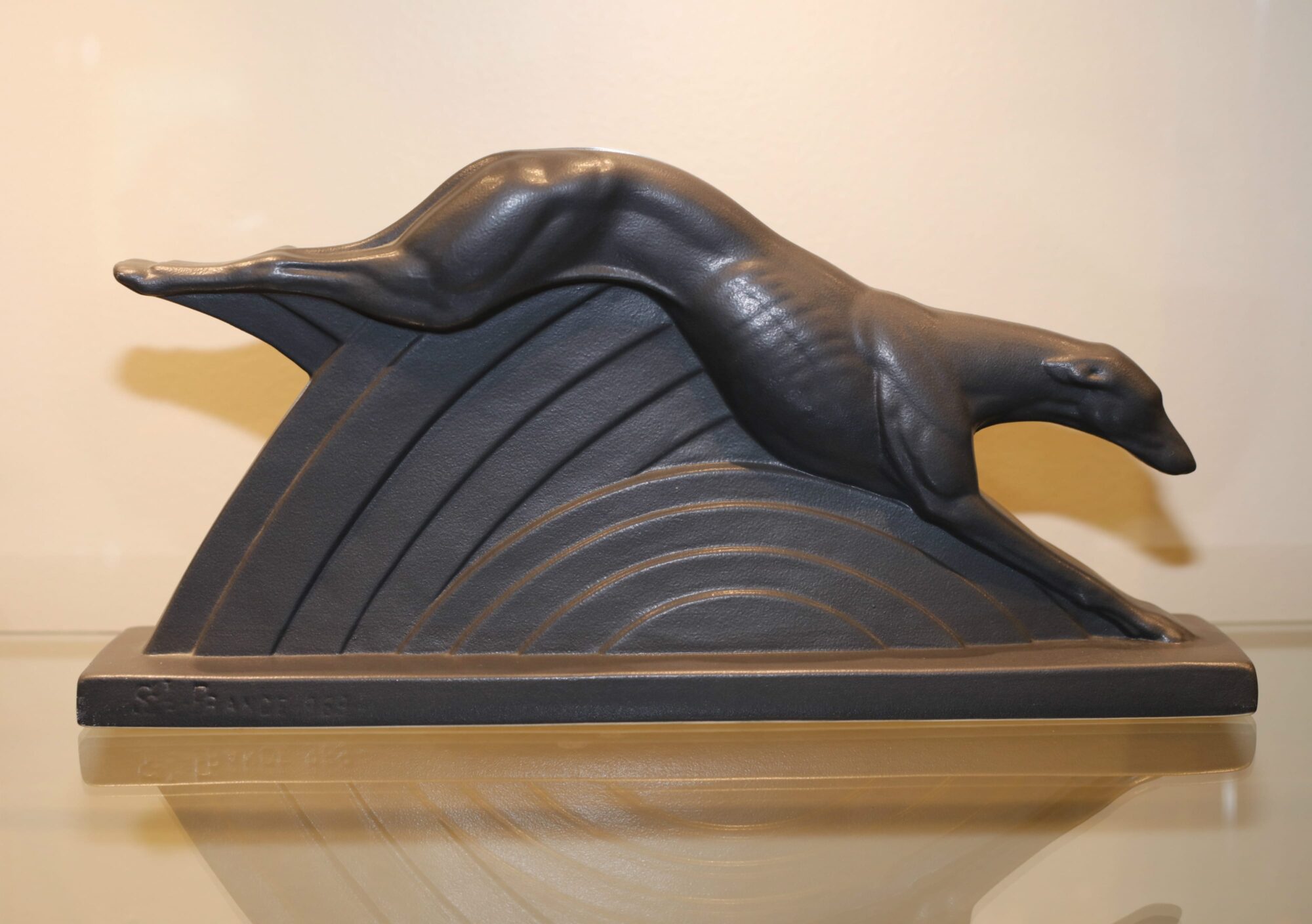 Stylized sculpture of a greyhound running.
