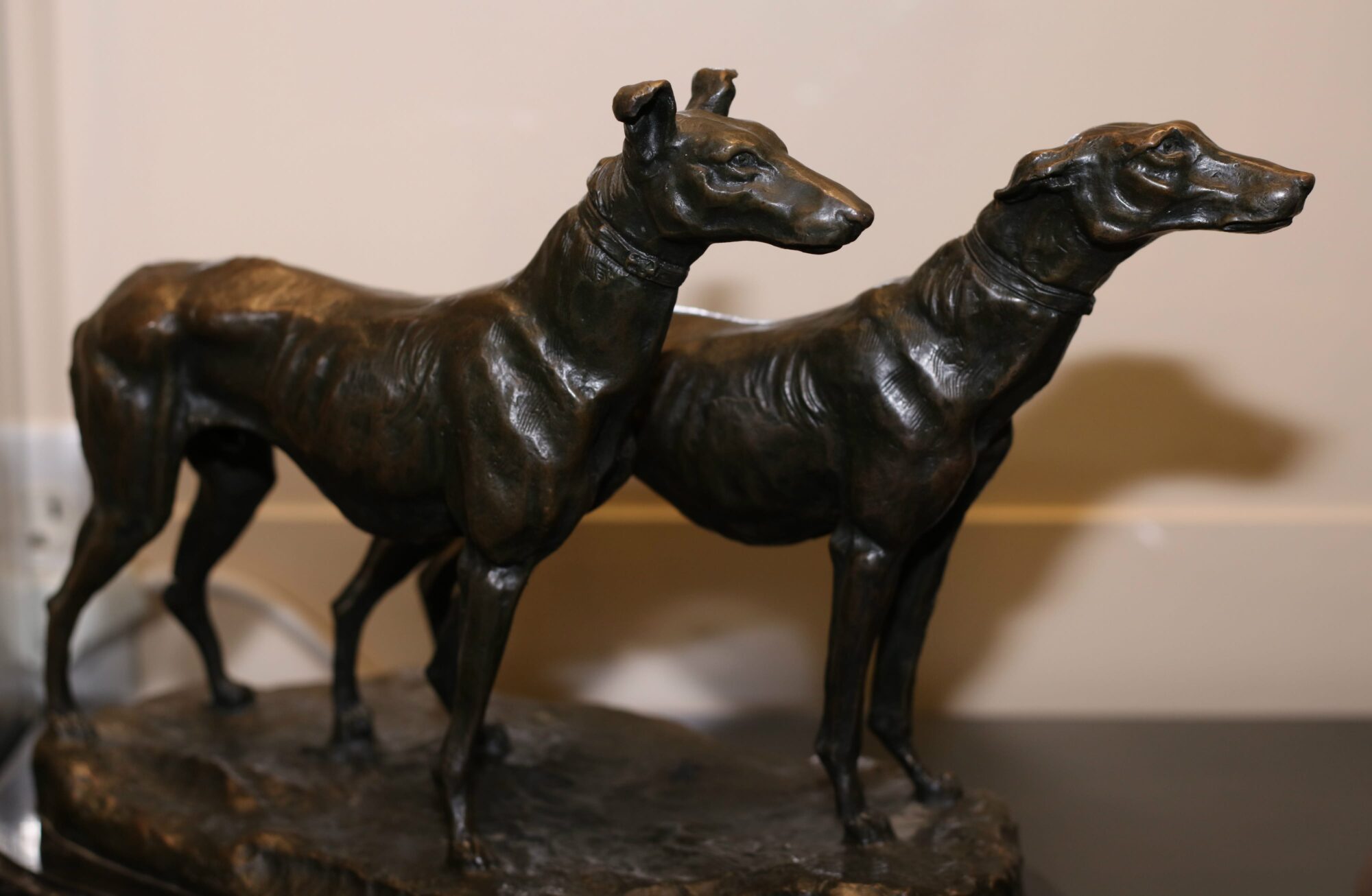 Sculpture of two greyhounds standing side by side on a marble base.