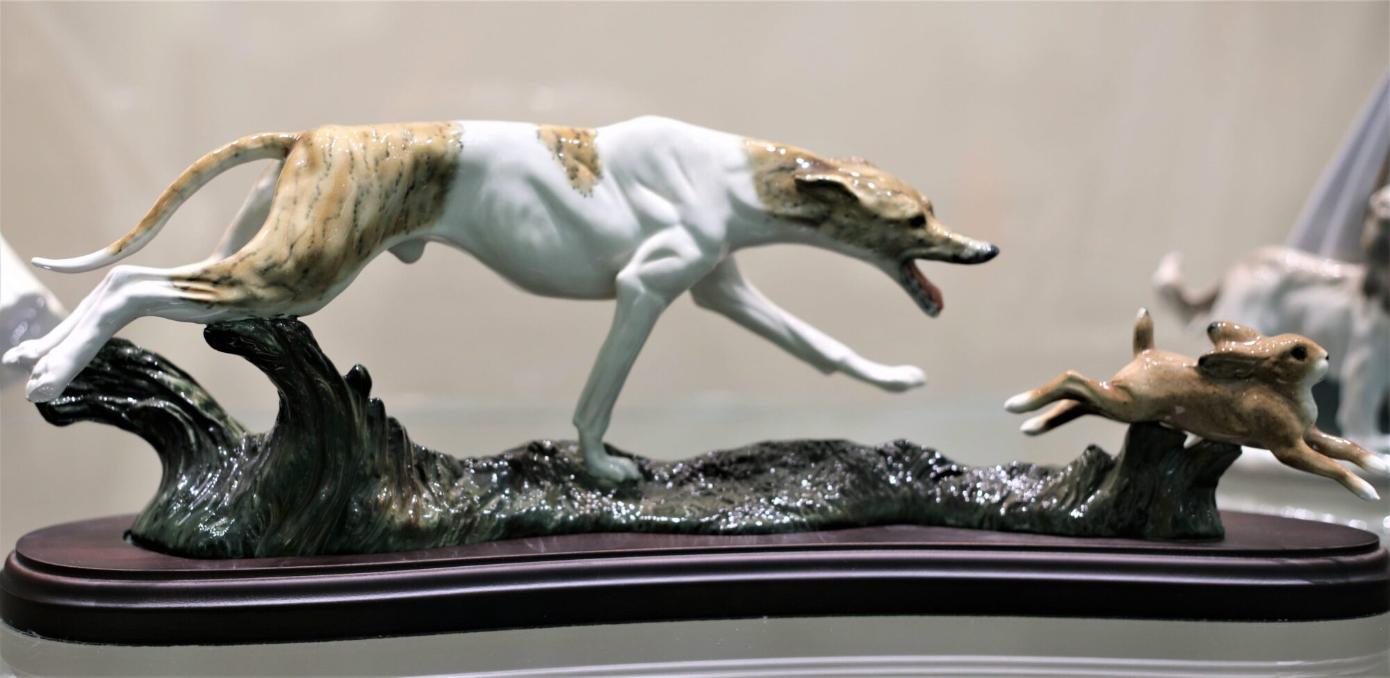 A realistic ceramic greyhound chasing a rabbit in profile.