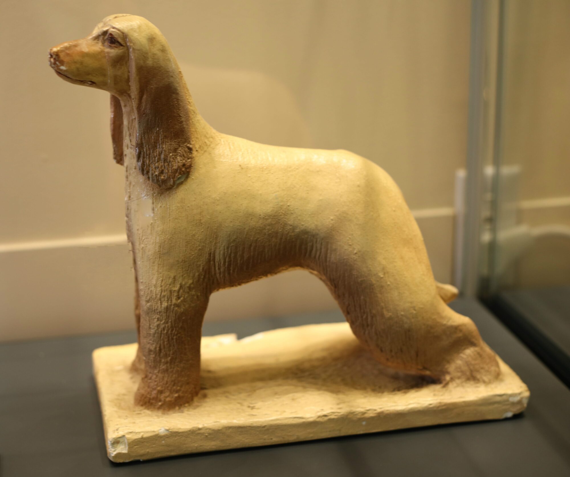Ceramic sculpture of a tan Afghan hound in profile.