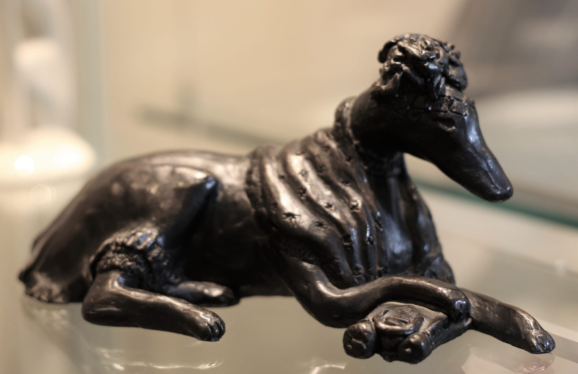 Sculpture of a sitting greyhound wearing clothing.
