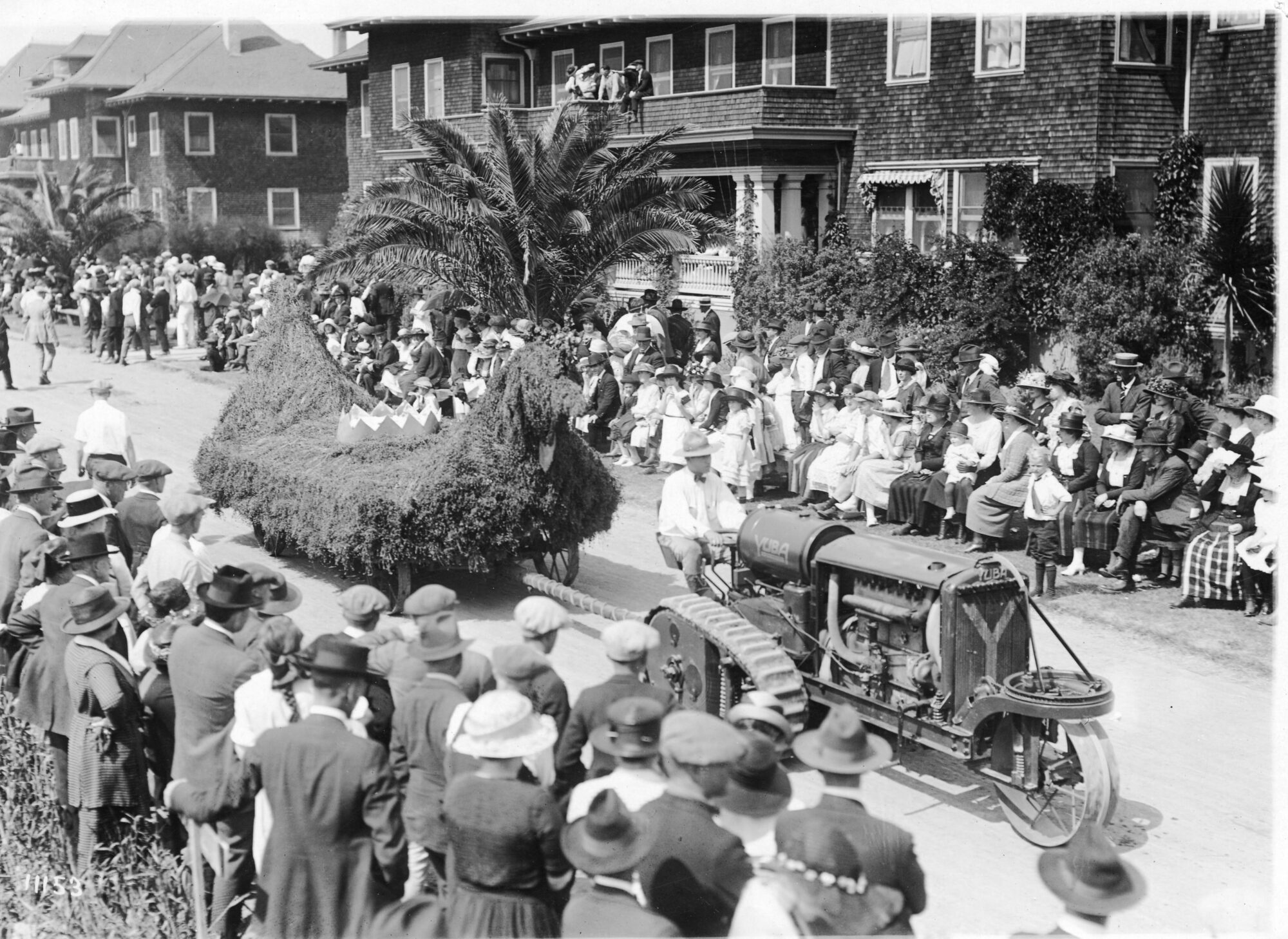 Tractor pulling a float through large crowd of people