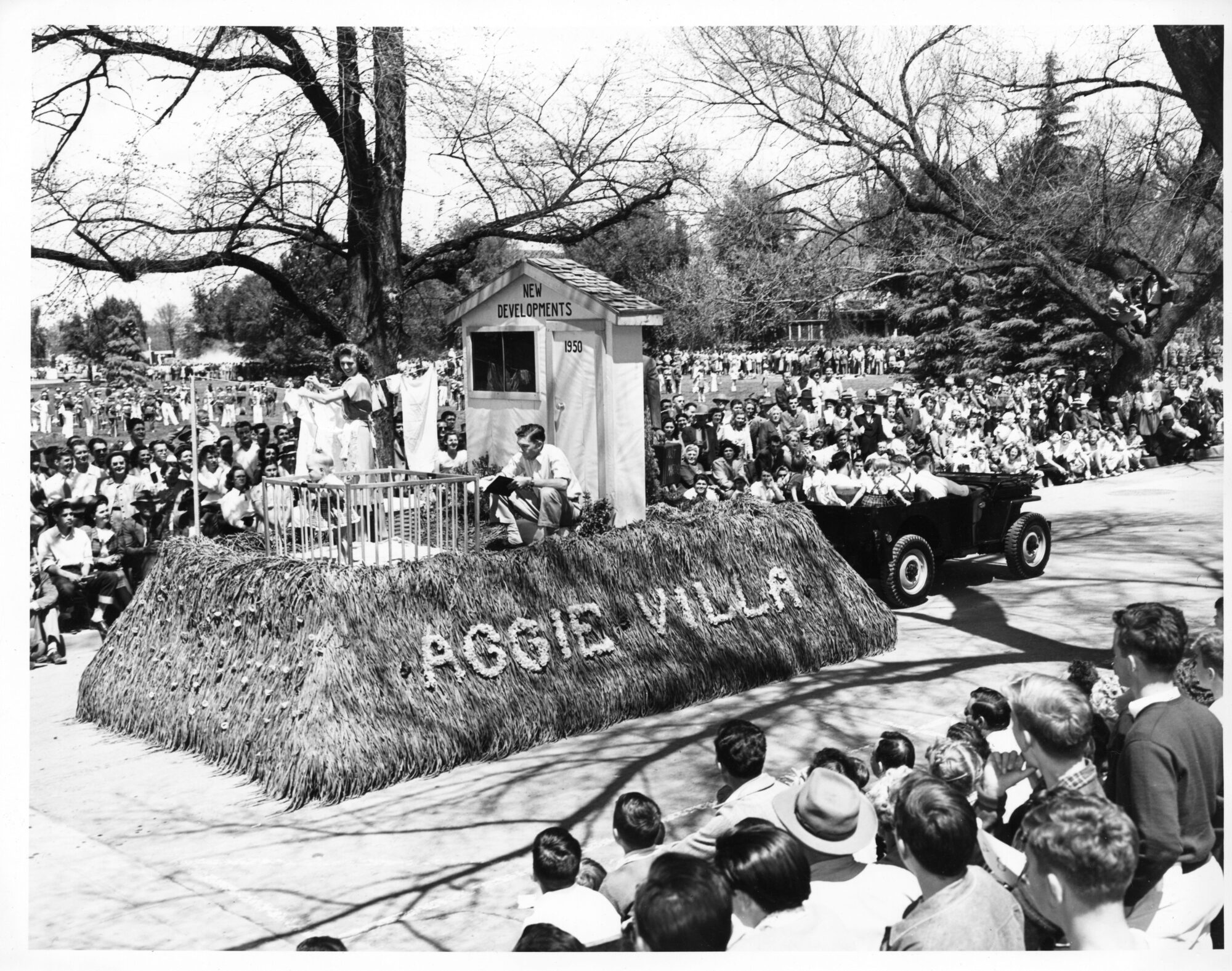Float representing family home life including a baby, hanging laundry, and read labeled as Aggie Villa
