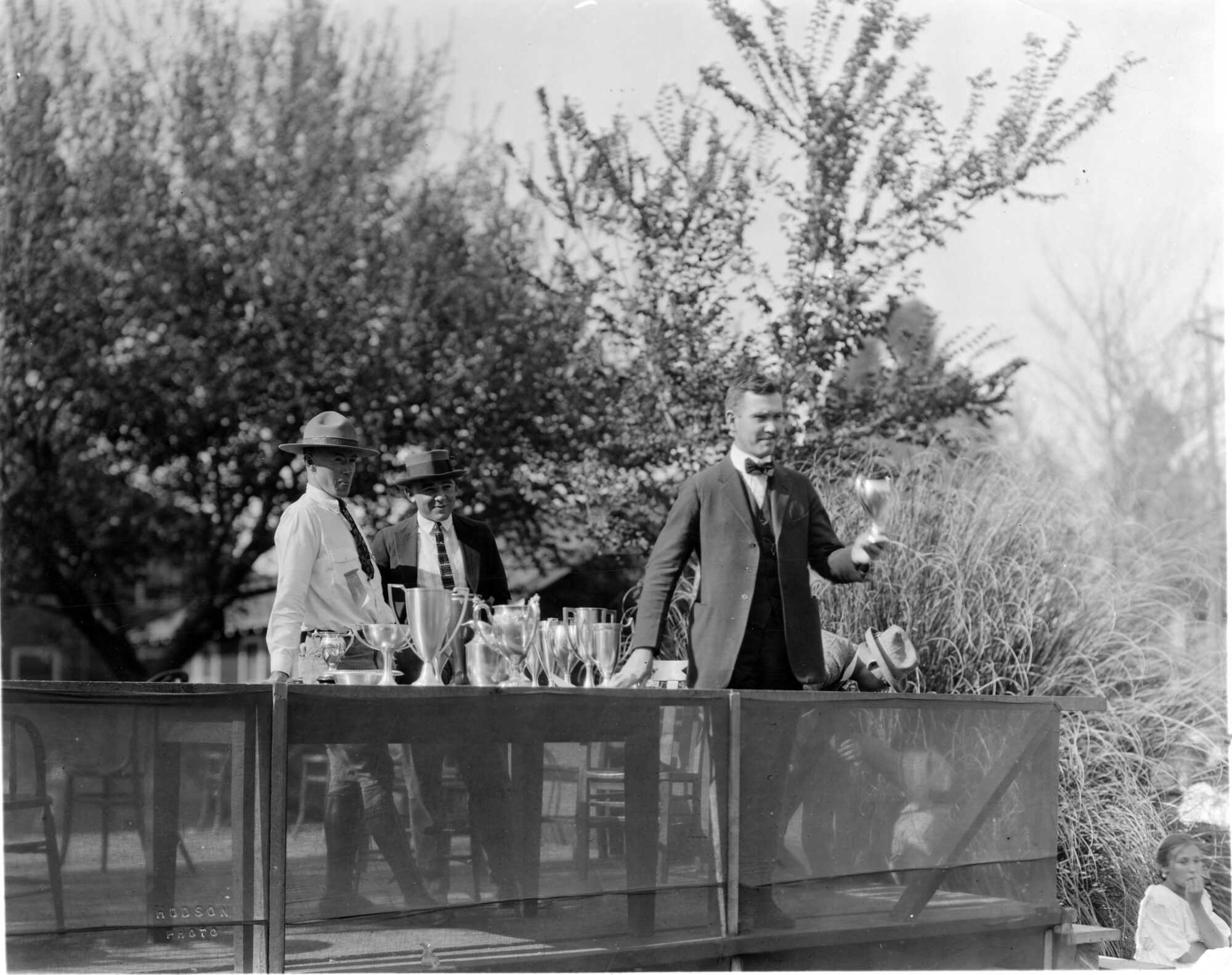 Man holding a trophy next to a table lined with trophies on a stage