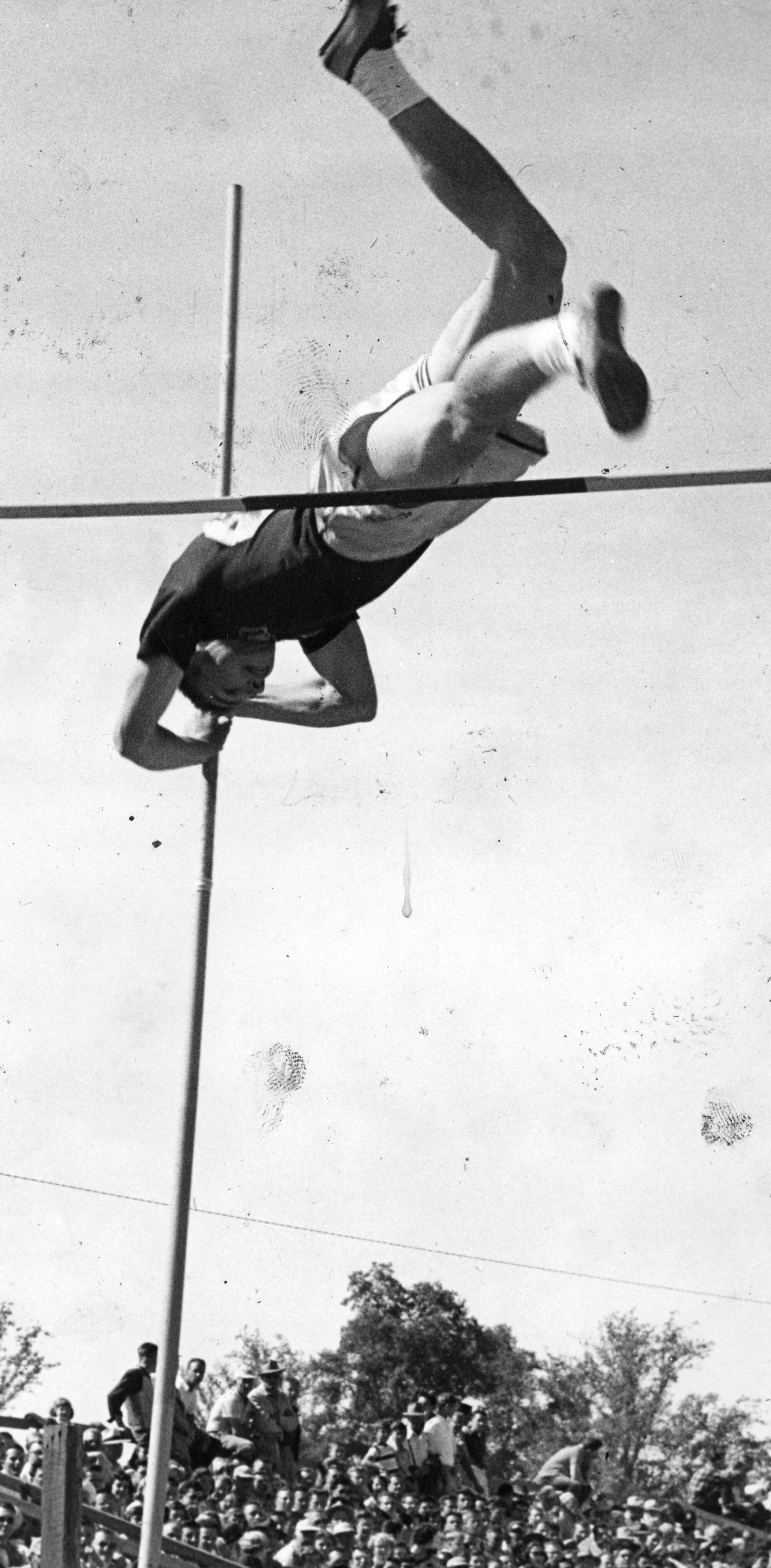 Man pole vaulting with onlookers in background