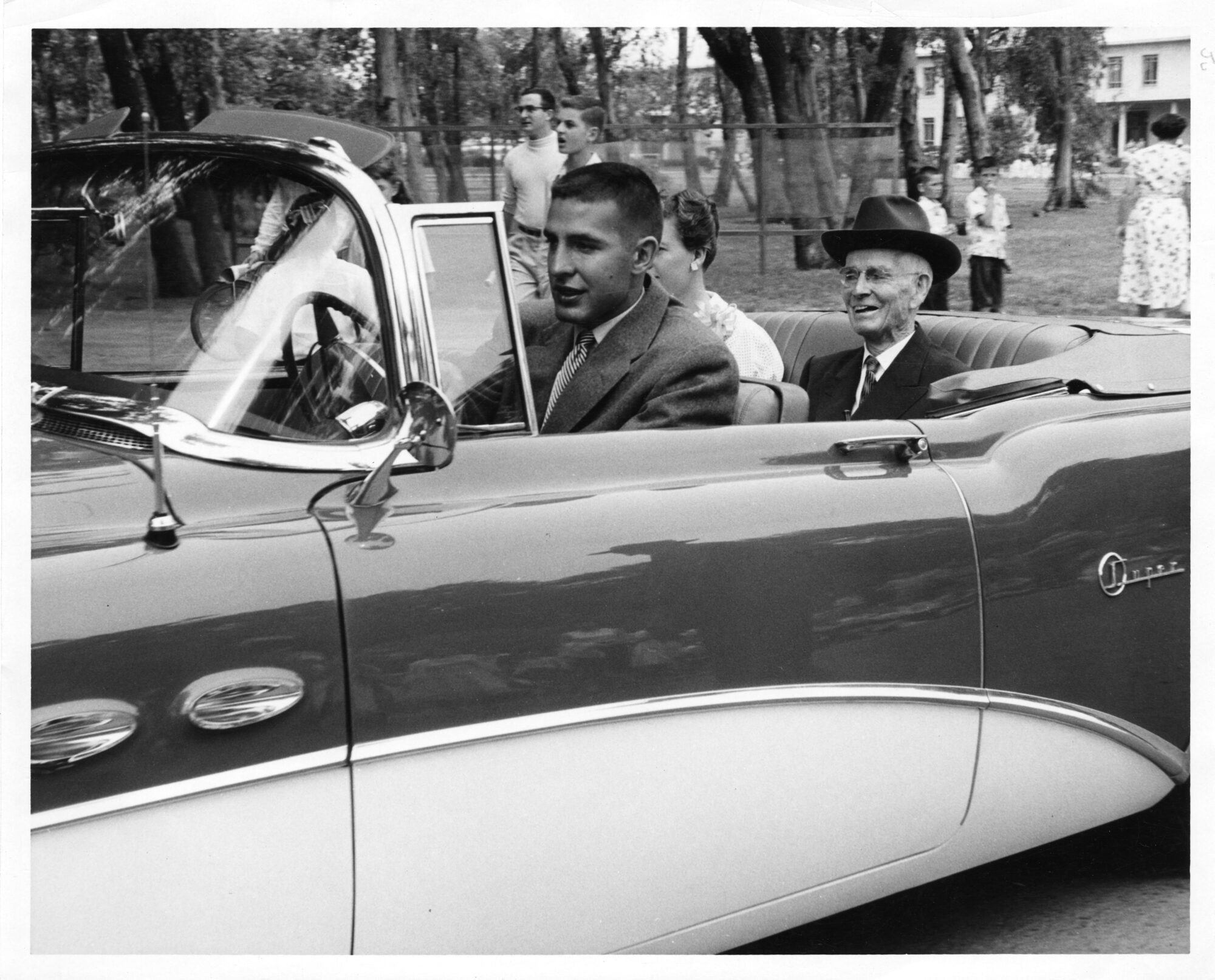Man riding in the back of an open top convertible car