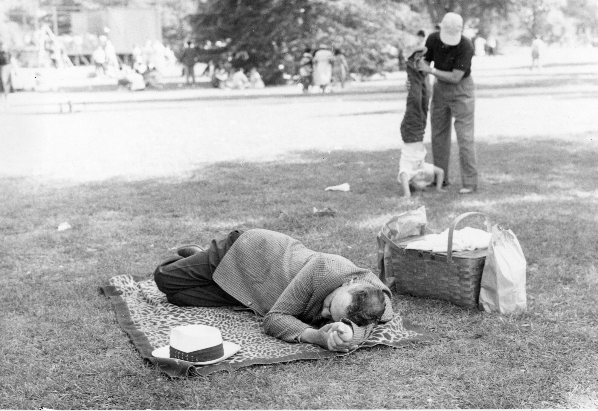 Man asleep on a picnic blanket next to a picnic basket