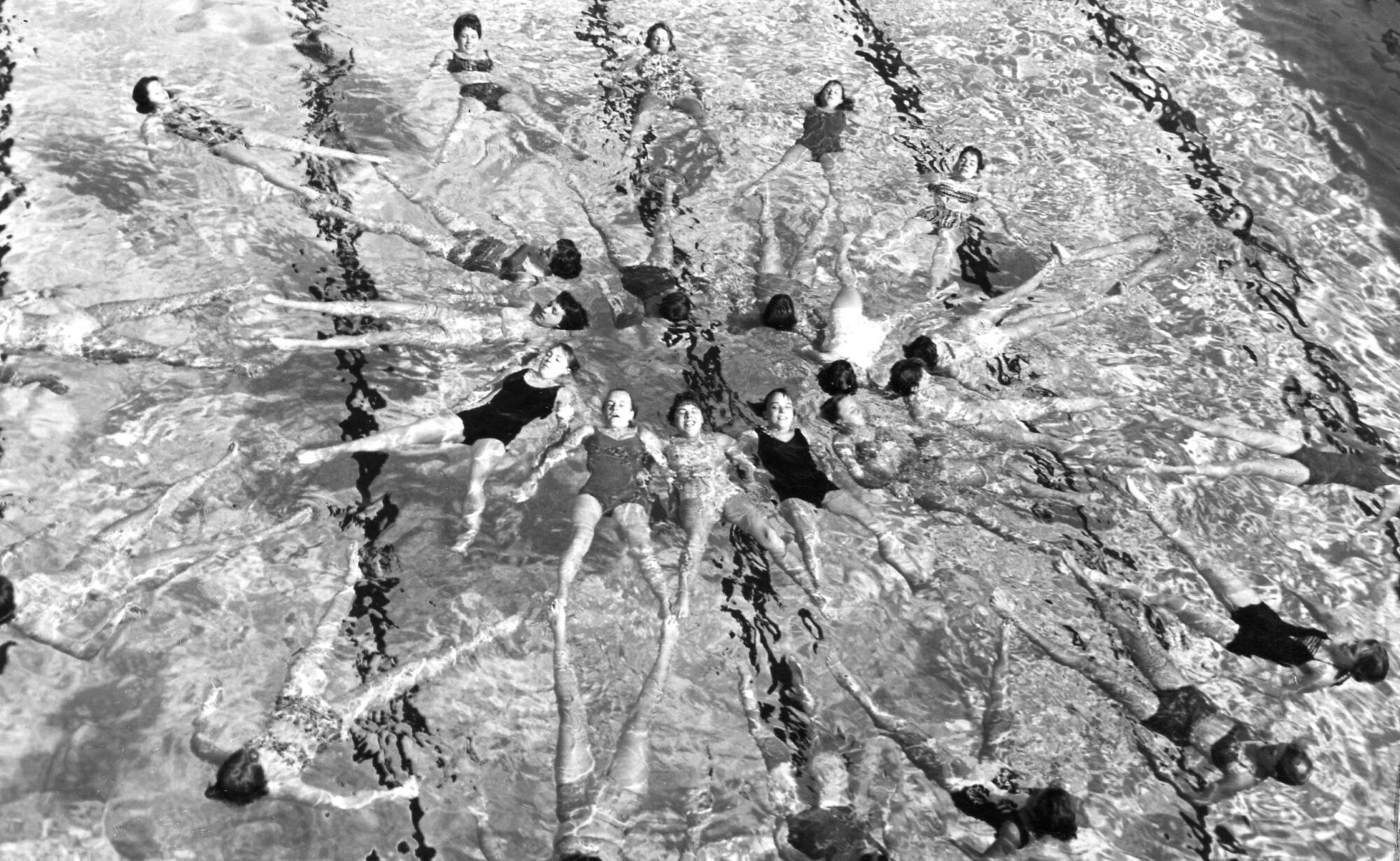 Group of floating swimmers holding hands in a circle formation