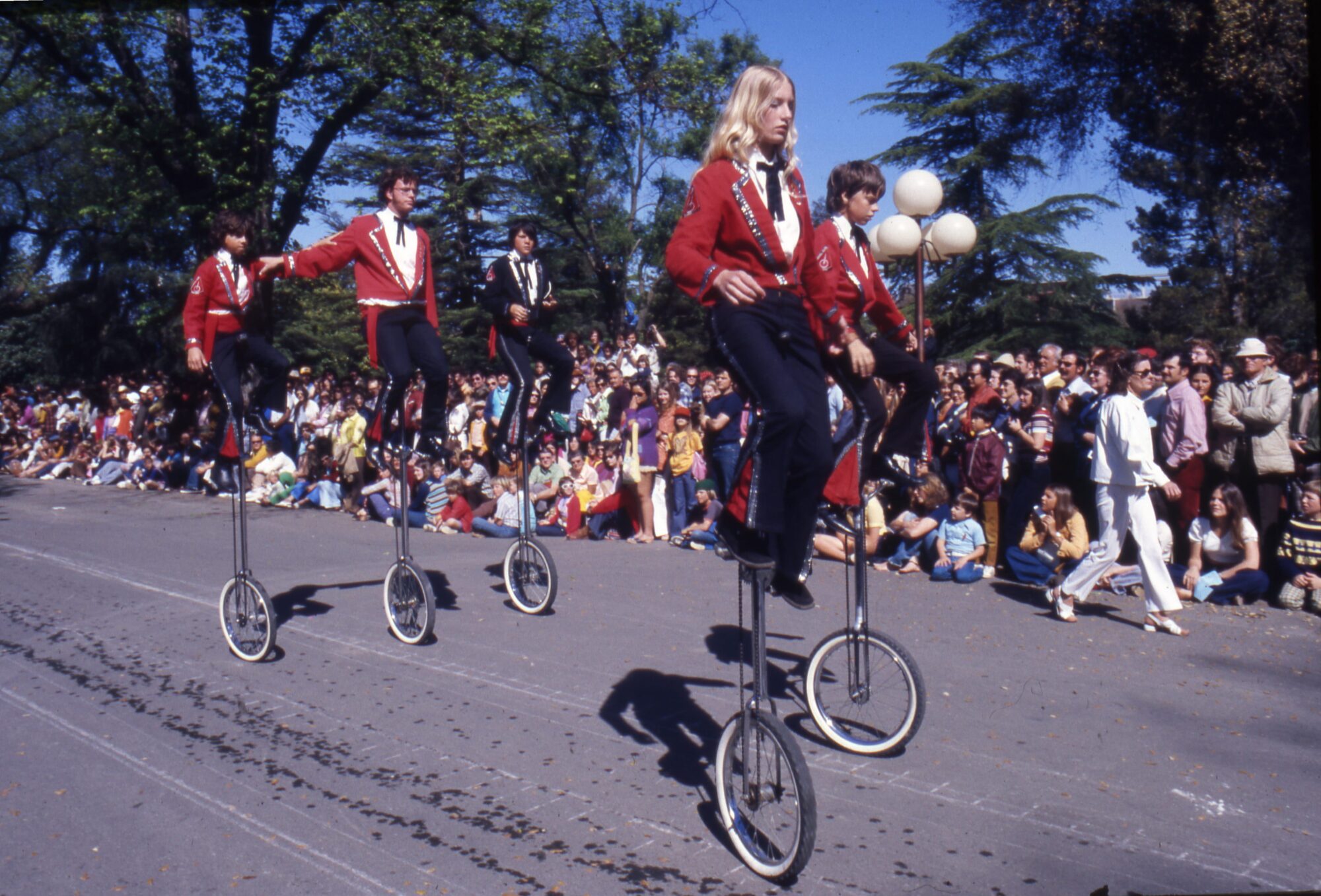 Uniformed people riding unicycles