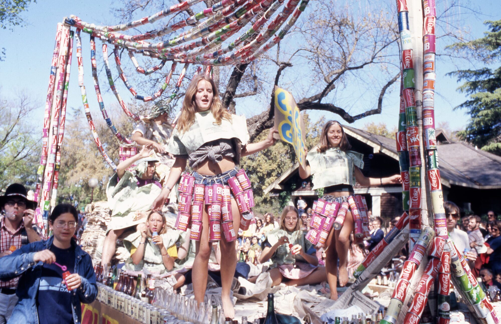 Float made with aluminum soda cans and glass bottles ridden by women wearing strings of cans as skirts