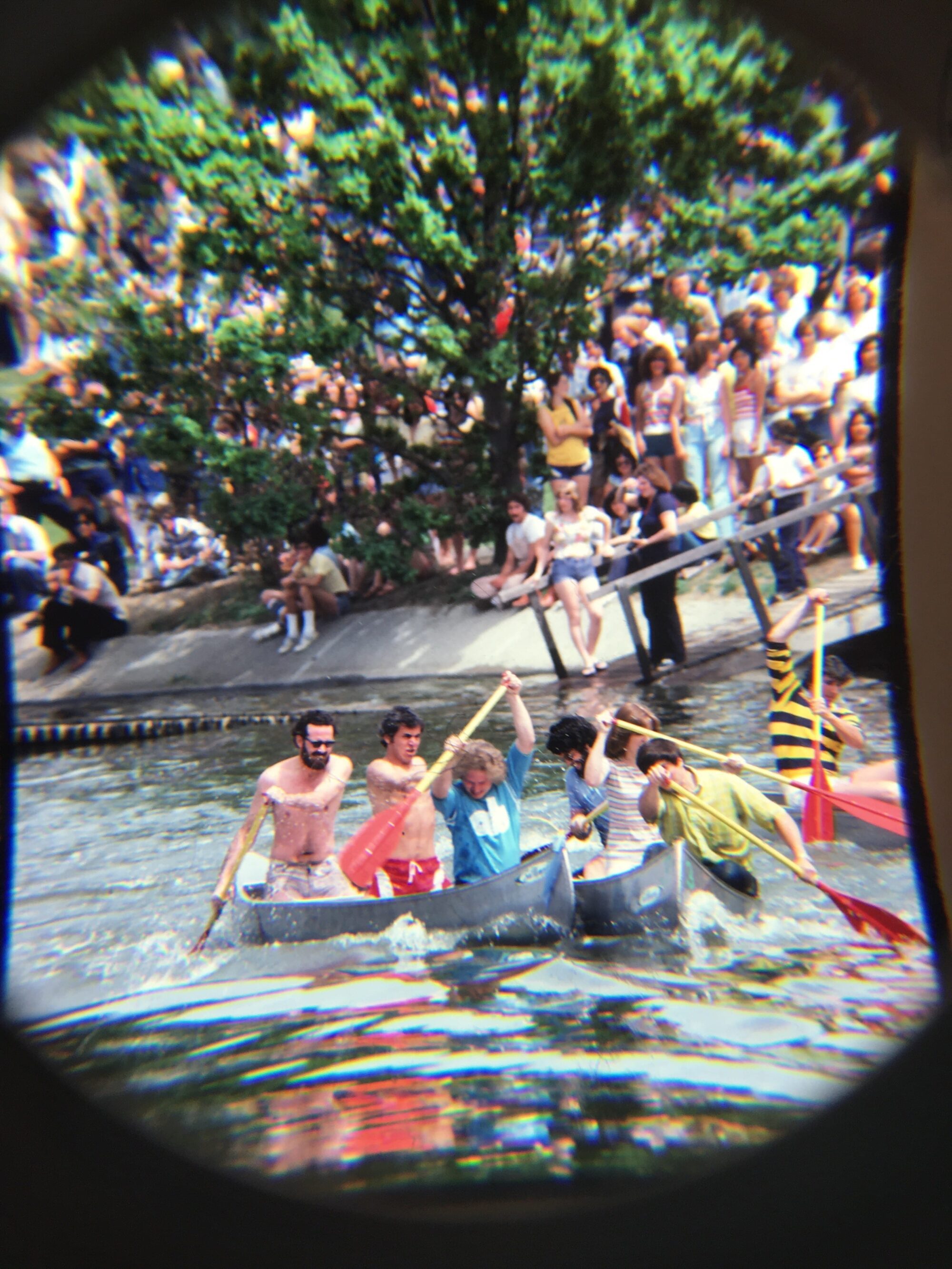 Metal canoes, each crewed by three people, racing on the water.