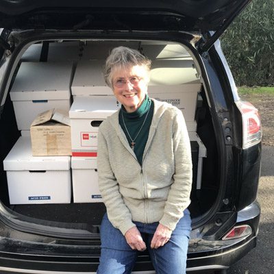 Gail Unzelman seated on the open trunk of an SUV filled with boxes of her wine literature.