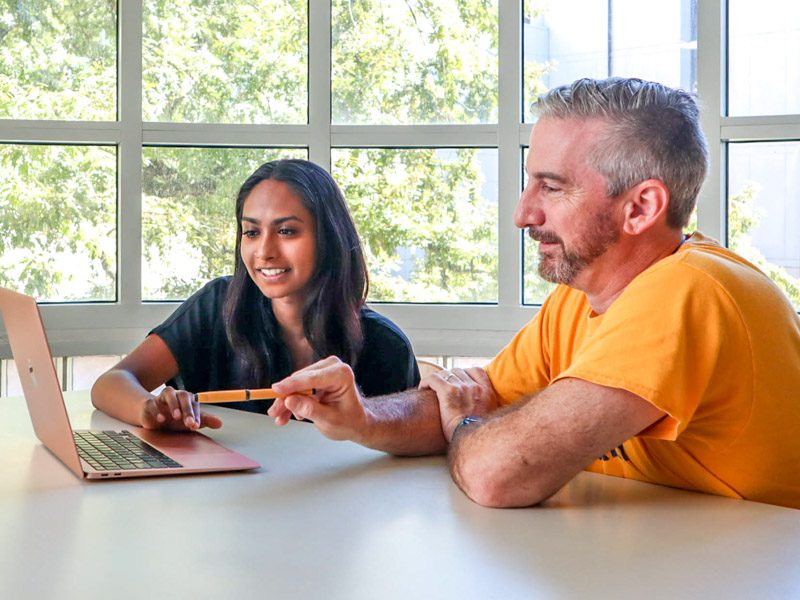 Librarian and student looking at a laptop discussing what's on the screen