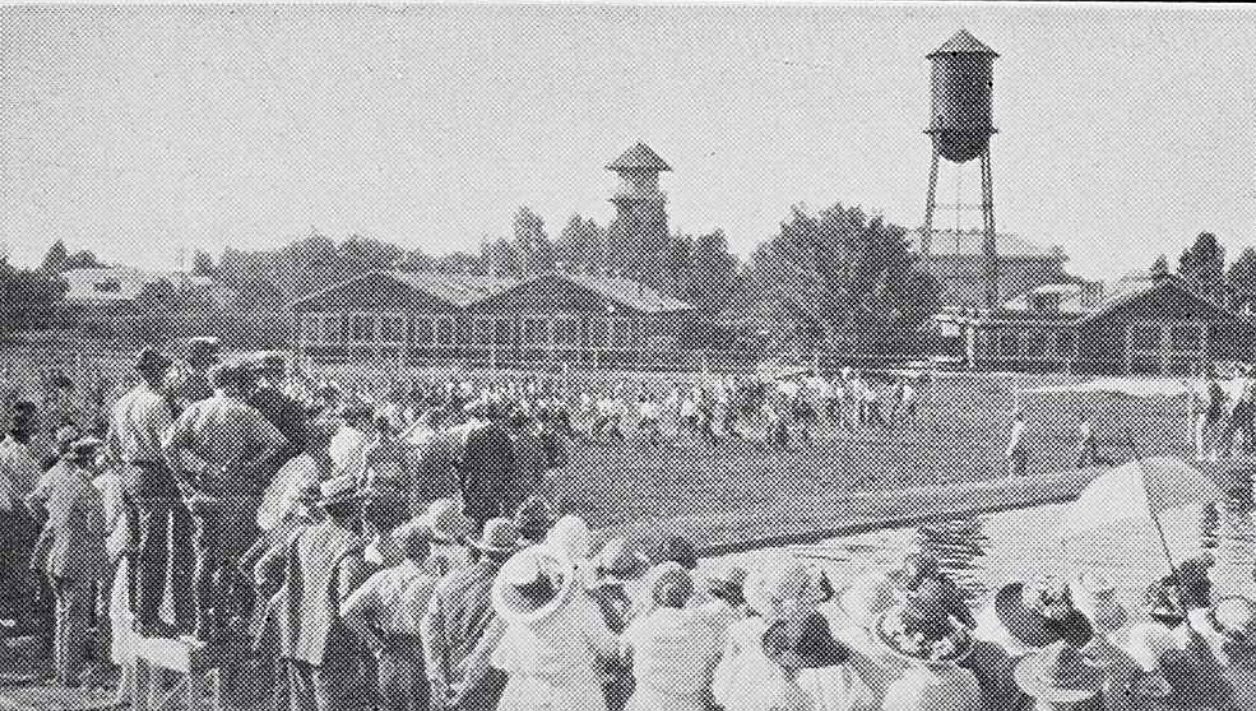 Group of people standing around a reservoir with two water towers in the background