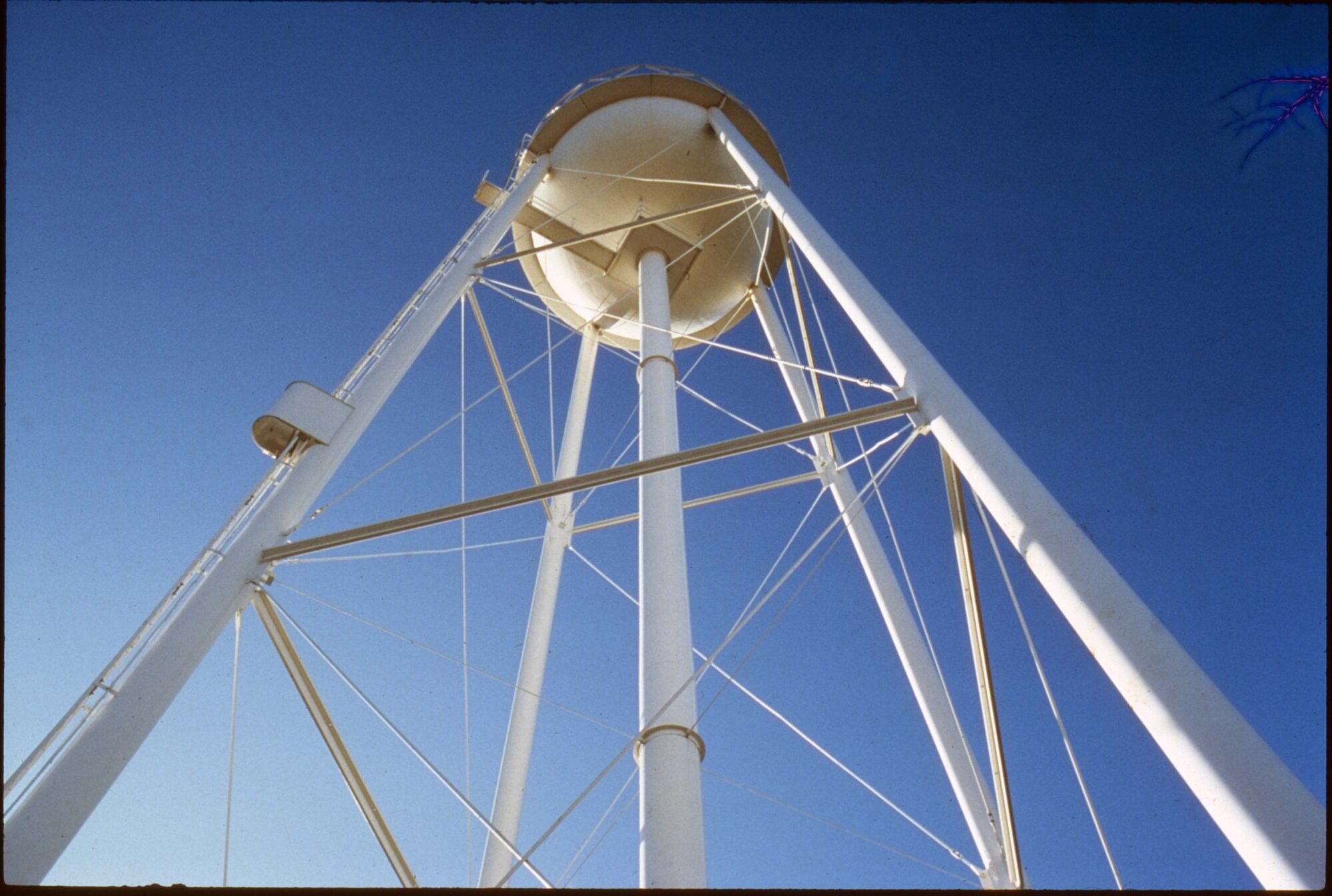 White water tower viewed from underneath against a blue sky