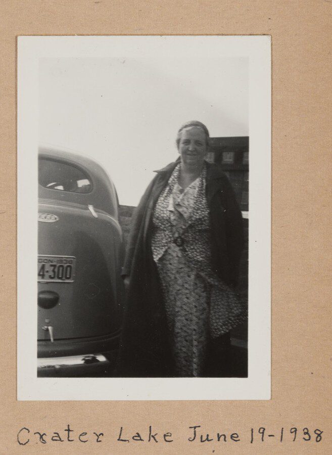 A woman standing next to a car at Crater Lake.