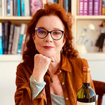 Woman sitting at a table with a bottle of wine