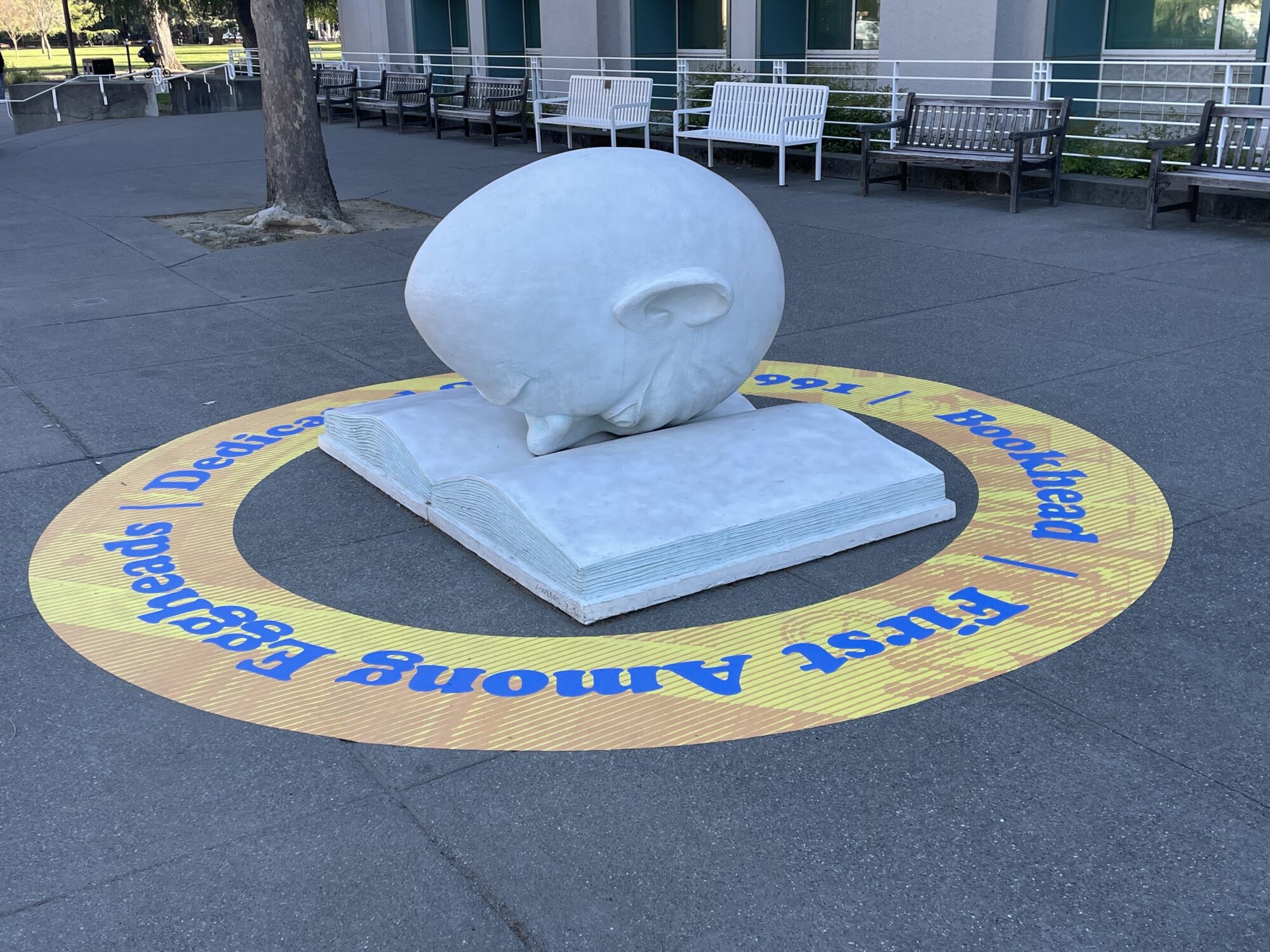 A large statue of an egg with a man's face looking down into a book.