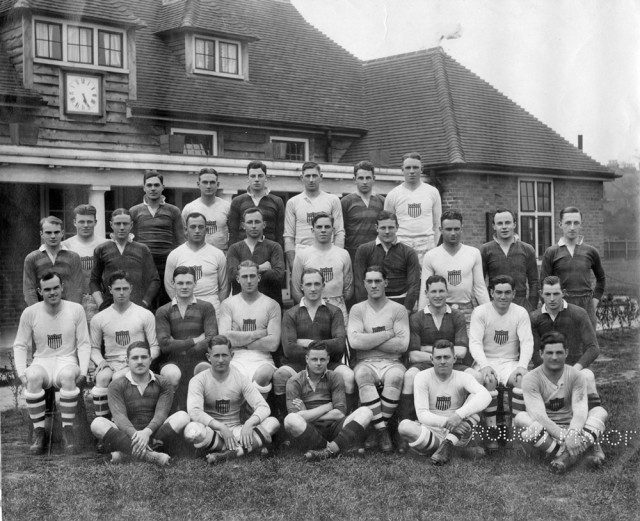 Men in rugby uniforms standing in front of a brick building