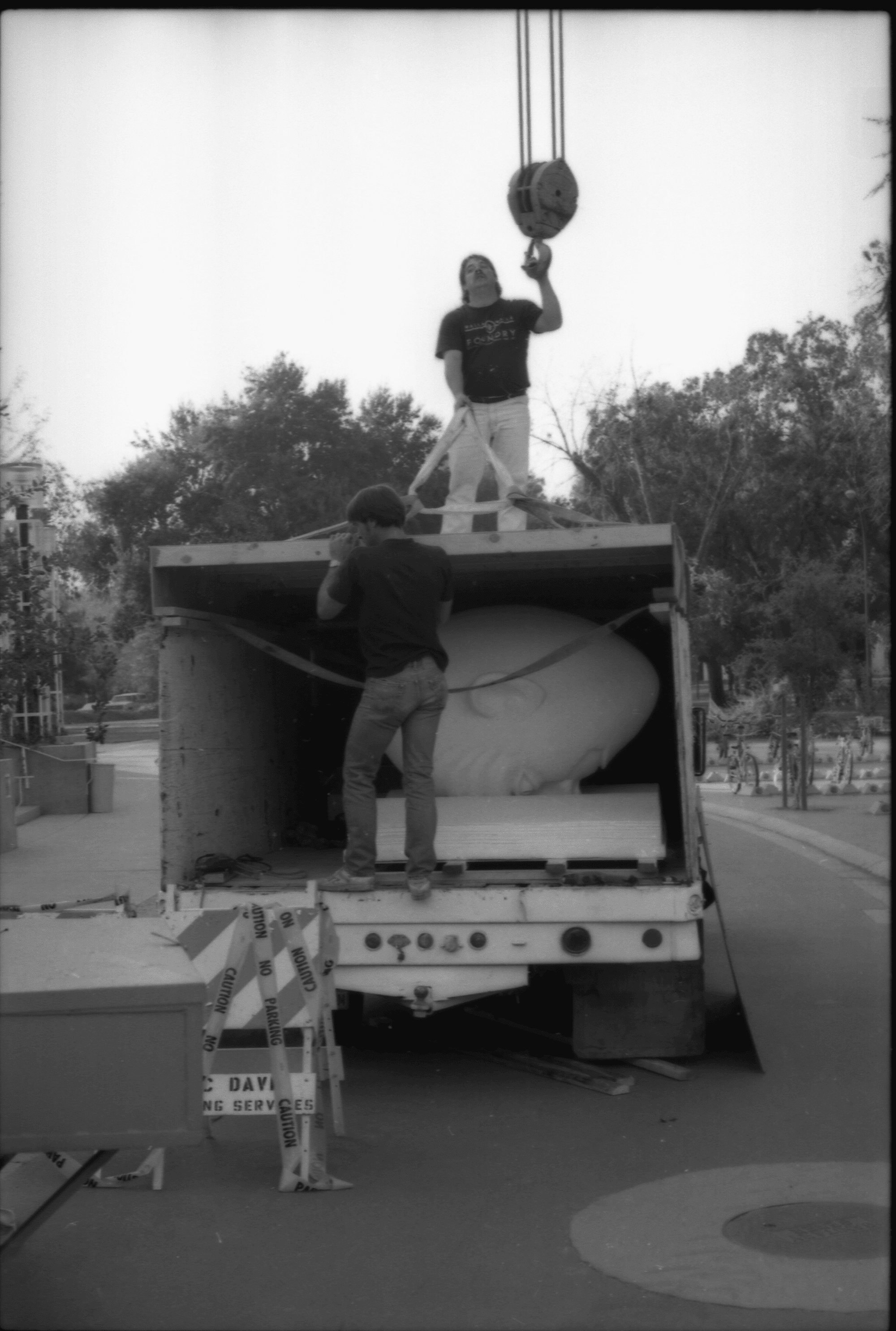 Two workers stand on a truck with the Bookhead sculpture inside.
