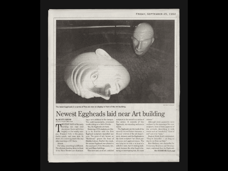 Newspaper clipping with a photo of the "Yin and Yang" Egghead sculpture: the Egghead in the foreground is on its side, the one in the background is upright.