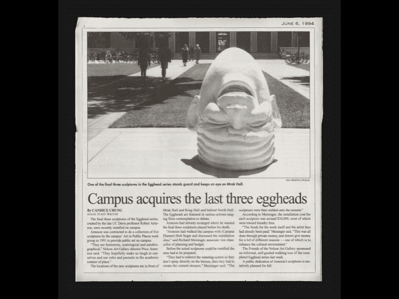 Newspaper clipping with a photo of the "Eye on Mrak" Egghead sculpture, an upside-down laughing head.