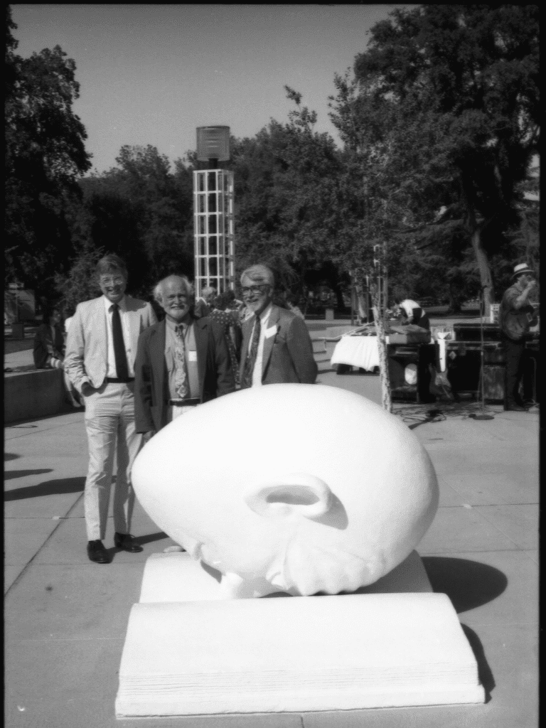 Three men pose by the Bookhead sculpture.