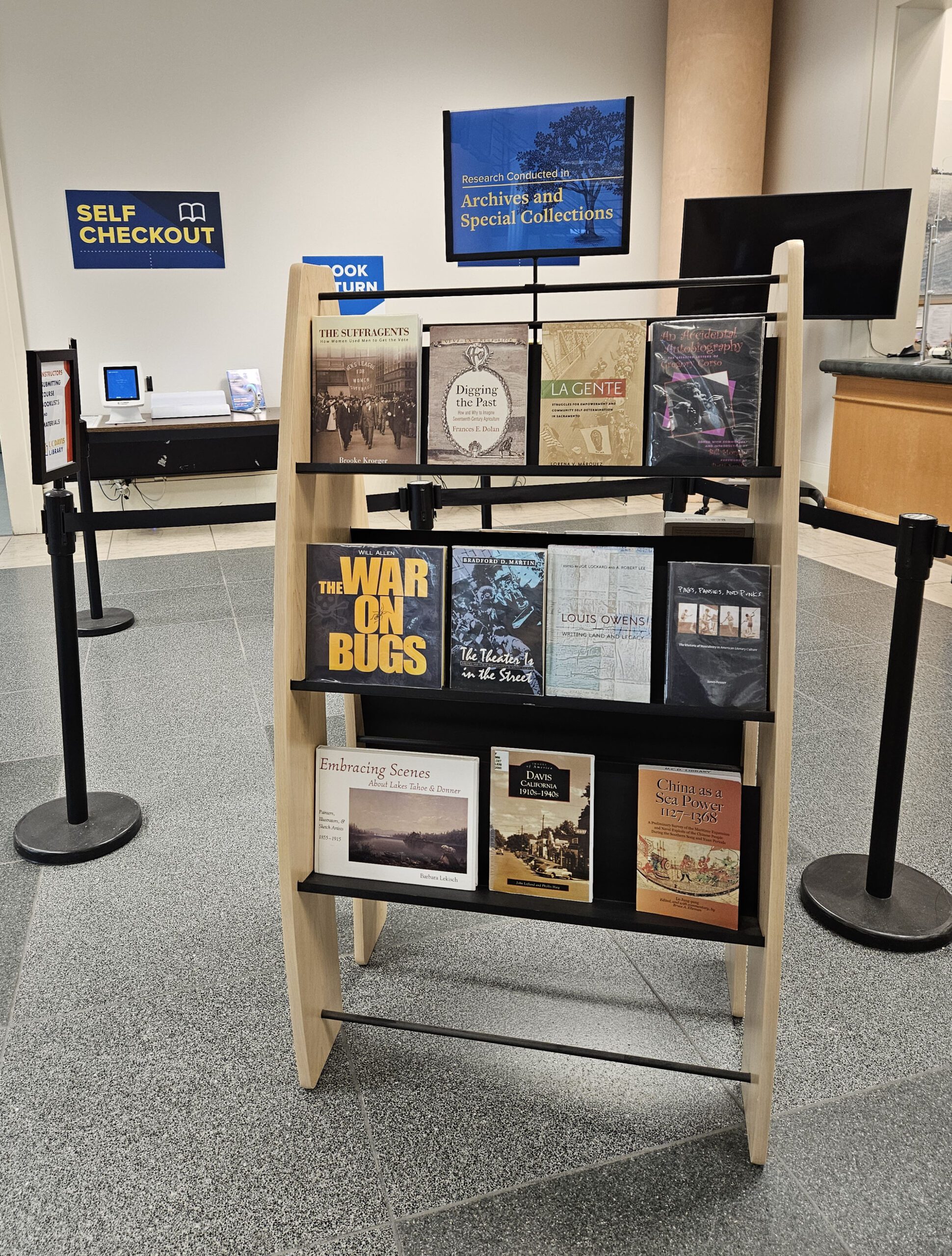 A bookshelf in front of the library circulation desk with several books on display.