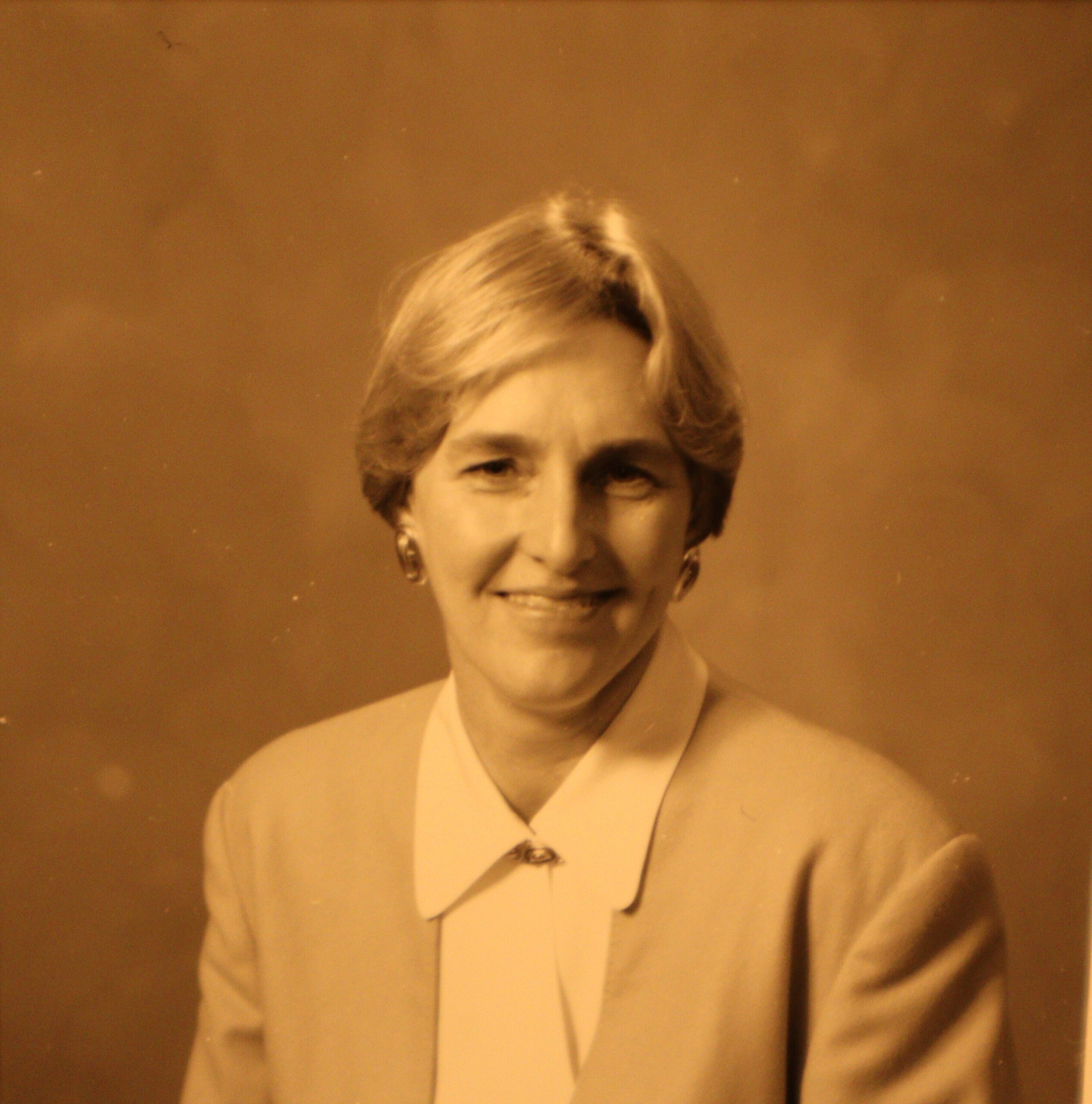 A sepia portrait of a woman with short, light-colored hair in a light jacket and blouse.