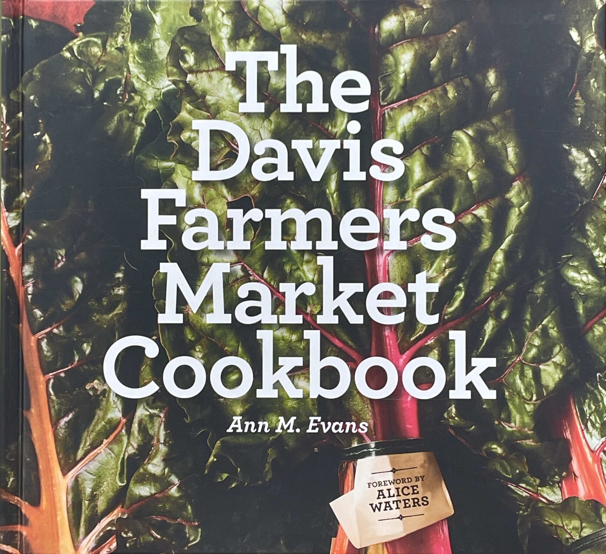The Davis Farmers Market Cookbook book cover with background of green, leafy vegetables. 