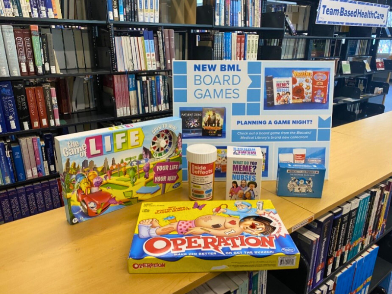 A sign and board games available to check out at BML, including Life and Operation.