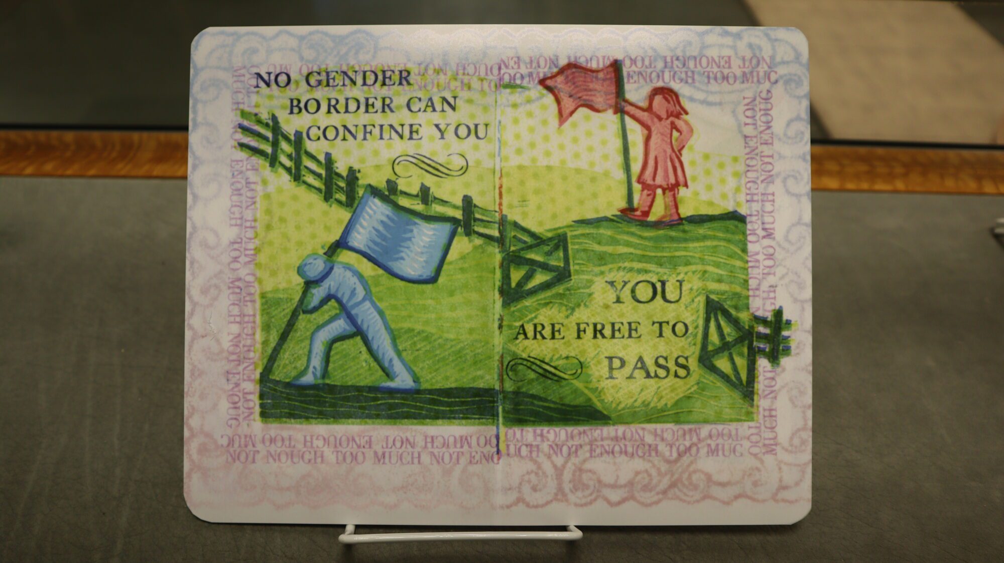 A facsimile of an artbook's pages, reading "No gender border can confine you. You are free to pass."