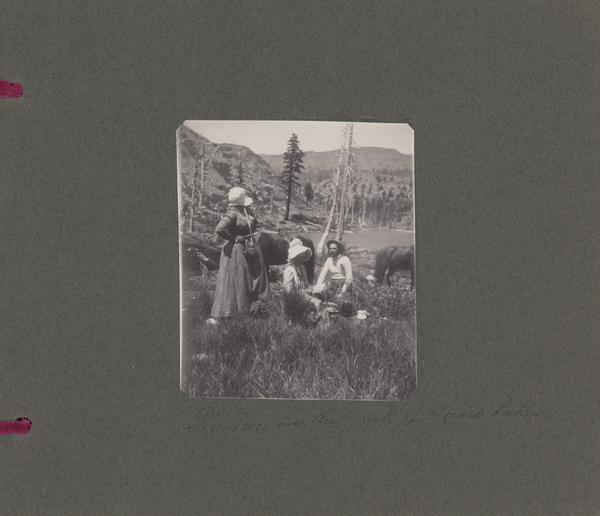 A black and white photograph of three people having a picnic by Susie Lake.