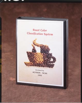 Binder cover for the Coffee Roast Classification System developed by Agtron - SCAA 1995. Illustration shows light and dark coffee beans in the shape of a steaming coffee cup.