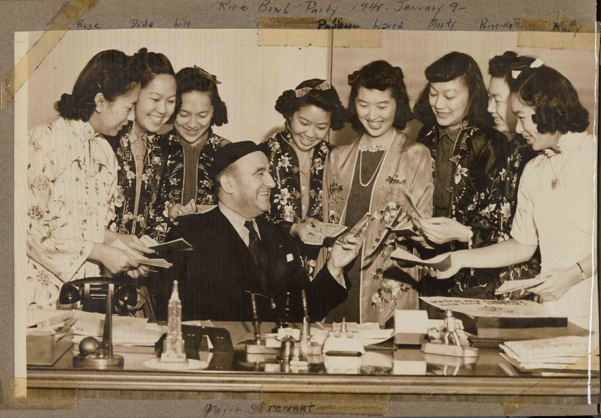A black and white photograph with a group of 8 women surrounding the mayor at a benefit party.