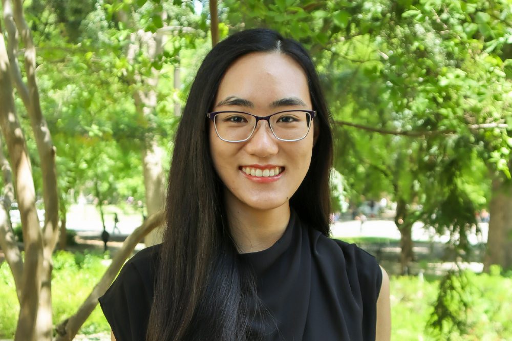 Portrait of Angelina Ong with trees and shrubs in the background.