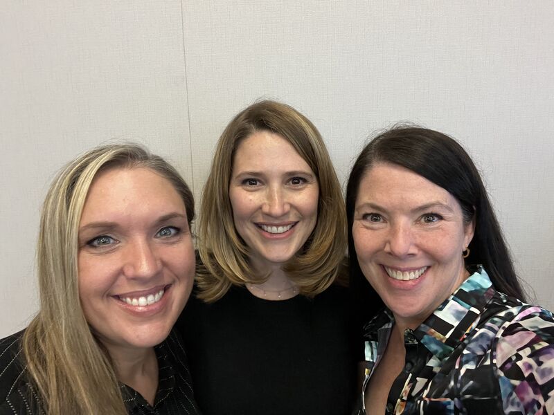 three women pose, smiling
